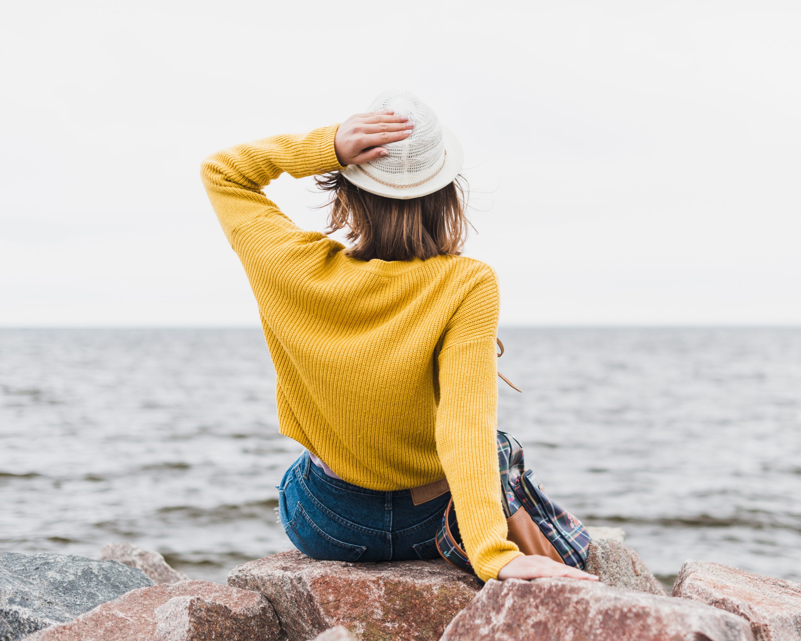 back-view-traveling-woman-facing-ocean girl sitting in front of sea